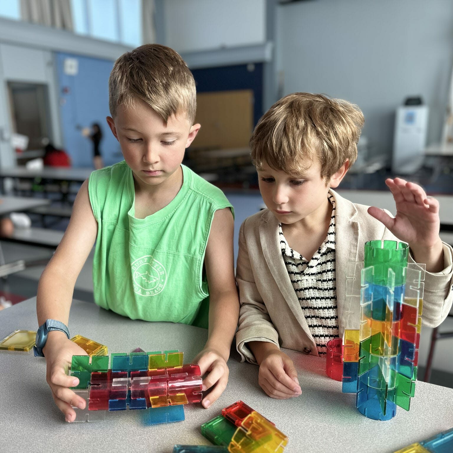 Two boys focused building colorful magnetic-tile structures at a table in a safe EnrichEd enrichment program space.